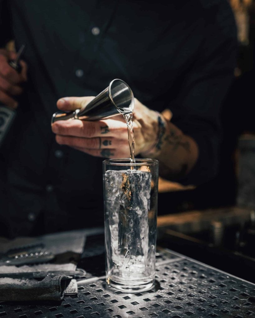 tattooed person preparing a olmeca tequila cocktail